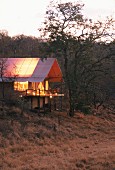 Beleuchtetes Ferienhaus in Abendstimmung in afrikanischer Landschaft