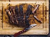 Overhead of cut BBQ pork ribs on a cutting board with a knife and bare bones