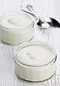 Naturjoghurt in Gläschen auf weißem Holztisch