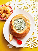 A loaf of bread filled with a cream cheese and spinach dip
