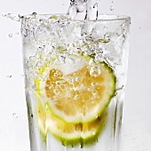 Water being poured into a glass of lime slices