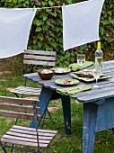 A vintage garden table laid for two with wine, salad and crackers
