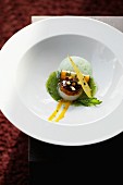 A fried scallop with vegetables rolls in stinging nettle sauce