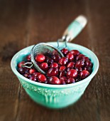 Fresh cranberries and a sieve in a bowl of water