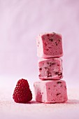 A stack of three raspberry marshmallow and a fresh raspberry