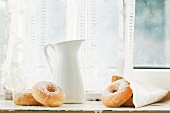 Sugar donuts and a white jug on old windowsill
