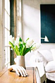 Still-life arrangement of plaster hand and vase of white hyacinths in loft-apartment interior