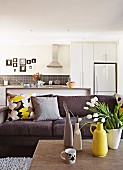 Sofa and collection of vases on coffee table in front of open-plan kitchen