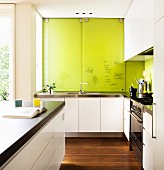 Moderne weiße Designerküche mit hellgrünen beschriftbaren Schrank-Schiebetüren hinter der Spüle