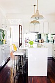 White. country-house-style fitted kitchen, bar stools and glossy wooden floor