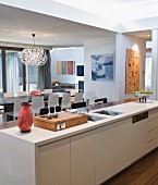 View past 60s ornaments on kitchen counter into open-plan living room with Dandelion designer lamp above dining table