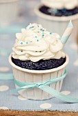 A chocolate cupcake decorated with buttercream and blue sugar pearls