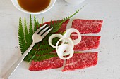Wagyu garnished with onion rings and fern leaves