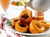 Gravy being poured over Yorkshire puddings