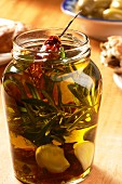 Olive oil with herbs, garlic and dried tomatoes in a screw-top jar