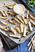 Baked celery sticks on a baking tray with a dip