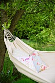 Floral cushion in ecru hammock hanging from tree