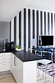 Open-plan kitchen with black worksurface on breakfast bar and bar stools; TV on sideboard against elegant, black and white striped wallpaper in background