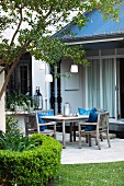 Wooden table & wooden chairs with blue scatter cushions on twilit terrace