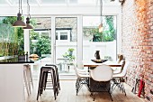 Modern dining area and island counter with bar stools in open-plan kitchen with exposed brickwork