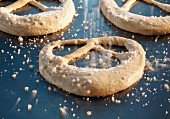 Unbaked pretzels being sprinkled with salt