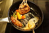 Venison with vegetables and herbs being fried in a pan