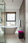 Violetter Deckel als Farbkleks in elegant modernem weißem Bad mit freistehender Wanne und dynamischem Wandmuster