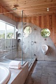 Designer Badezimmerecke mit verglastem Duschbereich und teilweise betonierter Wand in Boden übergehend