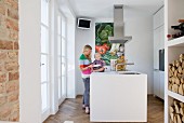 Woman and child in small, white designer kitchen with central island counter