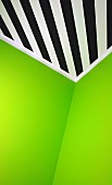 Grass green walls abutting ceiling painted with black and white diagonal stripes in corner