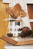 Decorated tin can and fir sprigs on open book