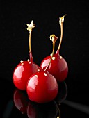 Three cocktail cherries decorated with gold leaf