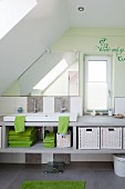 Children's attic bathroom - washstand on pale grey structure with storage, pastel green wall and message written next to narrow window