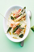 Asparagus skewers with ham and sage on a bed of creamy risotto