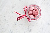 Raspberry bonbons in a jar on a marble surface