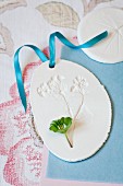 Pendant with impression of lady's mantle flower in plaster with blue ribbon