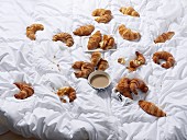 Croissants and a bowl of coffee on a bedspread