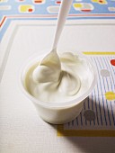Creamy yogurt in a pot with a plastic spoon