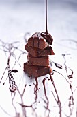 Gestapelte Schokoladenstücke mit Schokosauce begiessen