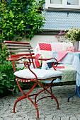 Vintage-Gartenstuhl auf Kopfsteinpflaster-Terrasse und gemütlicher Bank mit Patchworkdecke