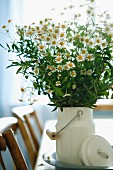 Bouquet of chamomile in white, nostalgic milk can on dining table