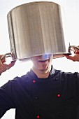 A chef holding a pot over his head