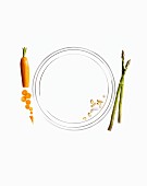 Pills on a plate with a carrot and green asparagus next to it