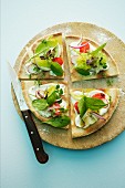 A salad pizza topped with radishes, cherry tomatoes and spinach