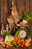 An autumnal arrangement featuring pheasants, vegetables, fruit, nuts and an old pair of kitchen scales