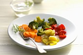 A plate of vegetables with carrots, leek, broccoli and peppers