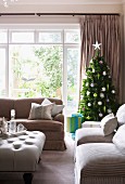 Sofa set and tray on ottoman in front of Christmas tree next to window