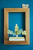Paper collage in simple oak picture frame on blue wall