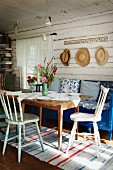 Küchenstühle und blauer Sitzbank um Holztisch in rustikalem Wohnraum eines Holzhauses