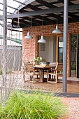 Industrieleuchten über Essplatz auf der überdachten Terrasse eines australischen 20er Jahre Wohnhauses mit Ziegelfassade